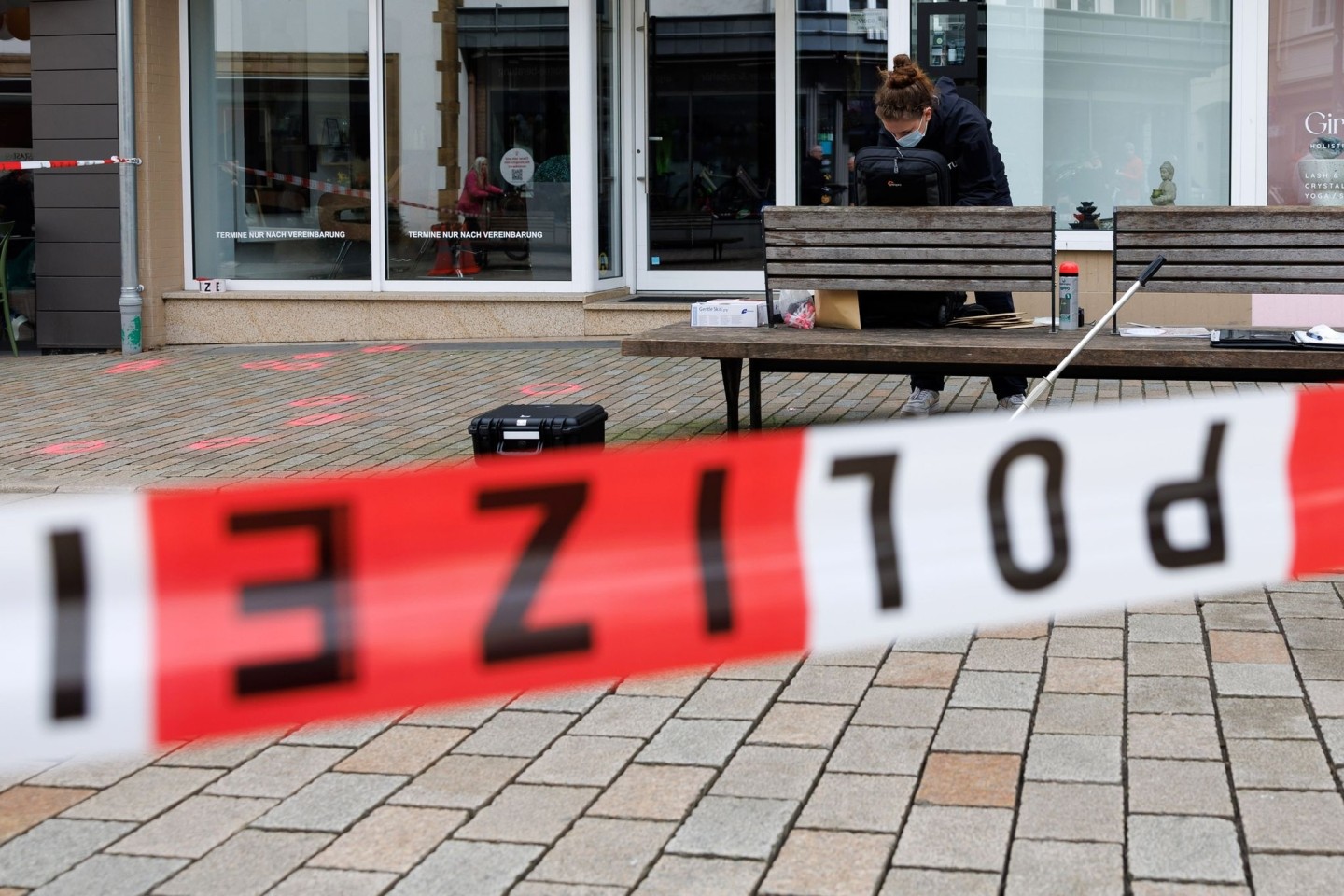 Eine Polizeibeamtin der Kriminaltechnik steht an einem abgesperrten Tatort.