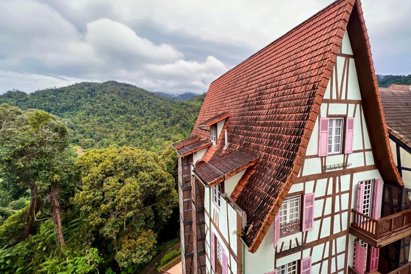 Hinter einem Fachwerkhaus in Colmar Tropicale ist der Dschungel der Berjaya Hills zu sehen.