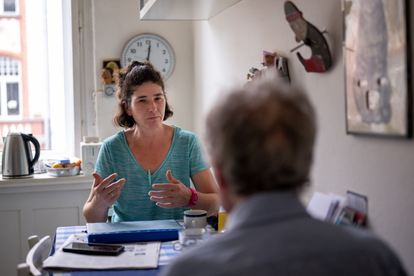 Die Pflegerin Ramona Rössner spricht beim Hausbesuch mit einem pflegebedürftigen Patienten.