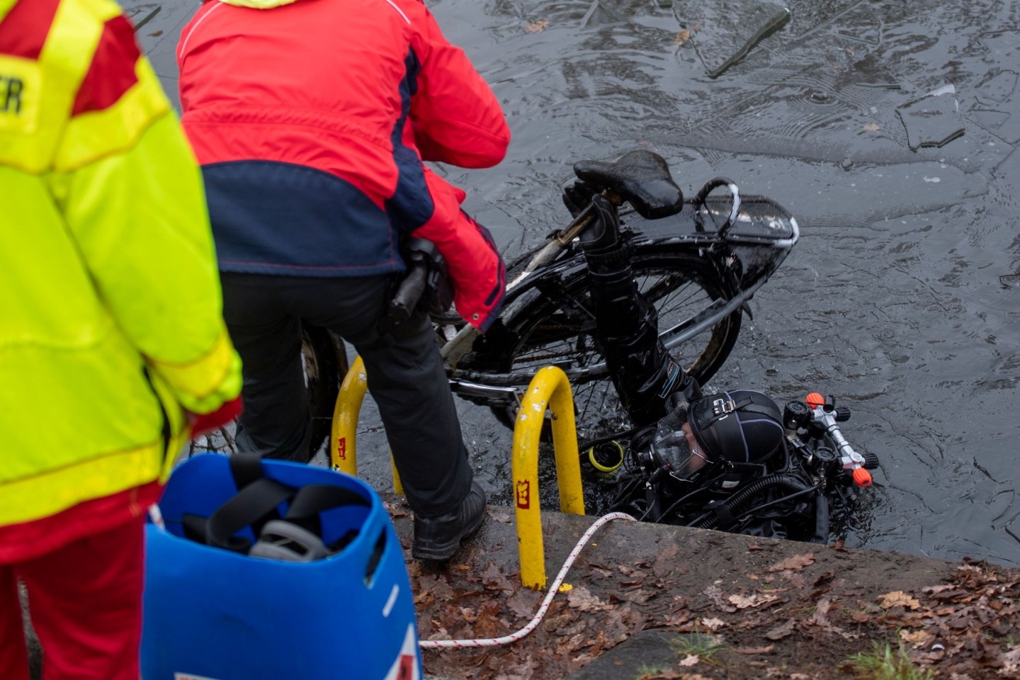 Ein Polizeitaucher hebt ein Fahrrad aus dem Schifffahrtskanal.