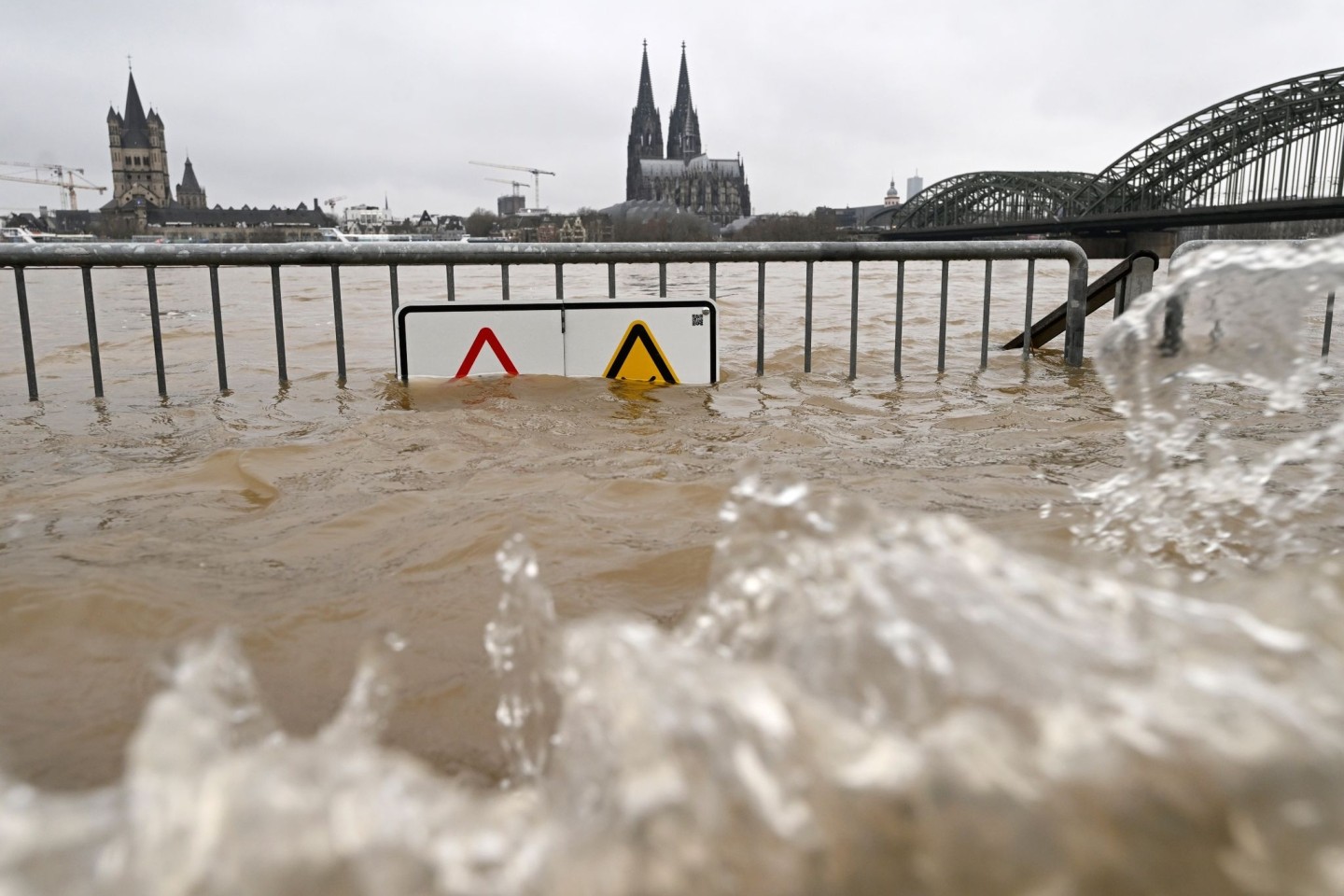 Blick auf den Hochwasser führenden Rhein vor dem Dom und der Hohenzollernbrücke.