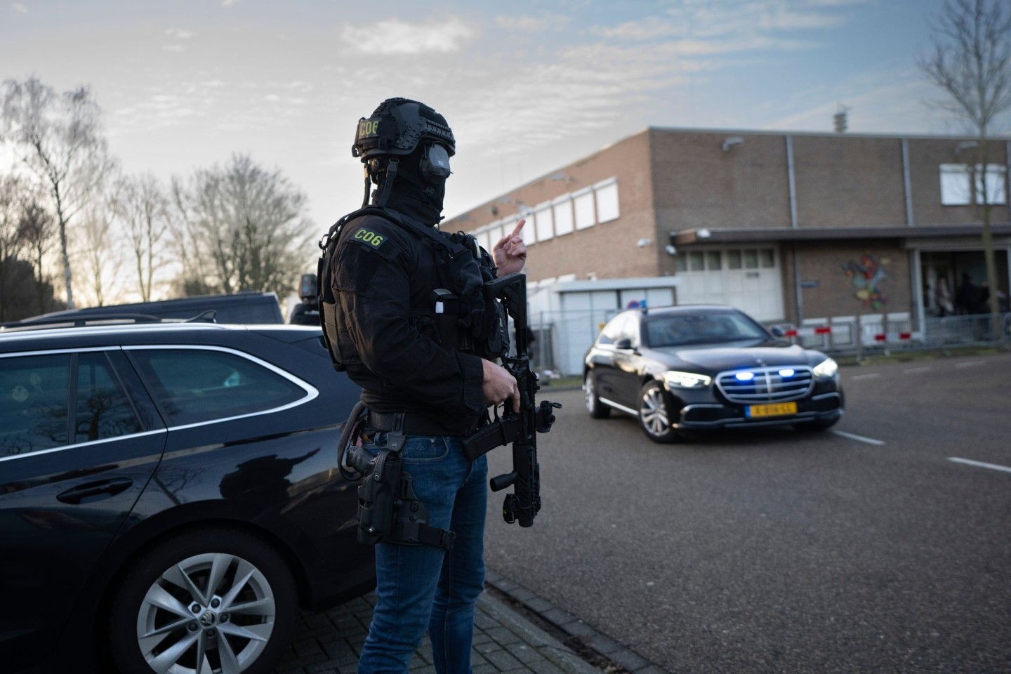 Maskierte und bewaffnete niederländische Polizisten bewachen einen Transport mit einigen der Verdächtigen, die vor dem Hochsicherheitsgebäude des Gerichts in Amsterdam eintreffen.