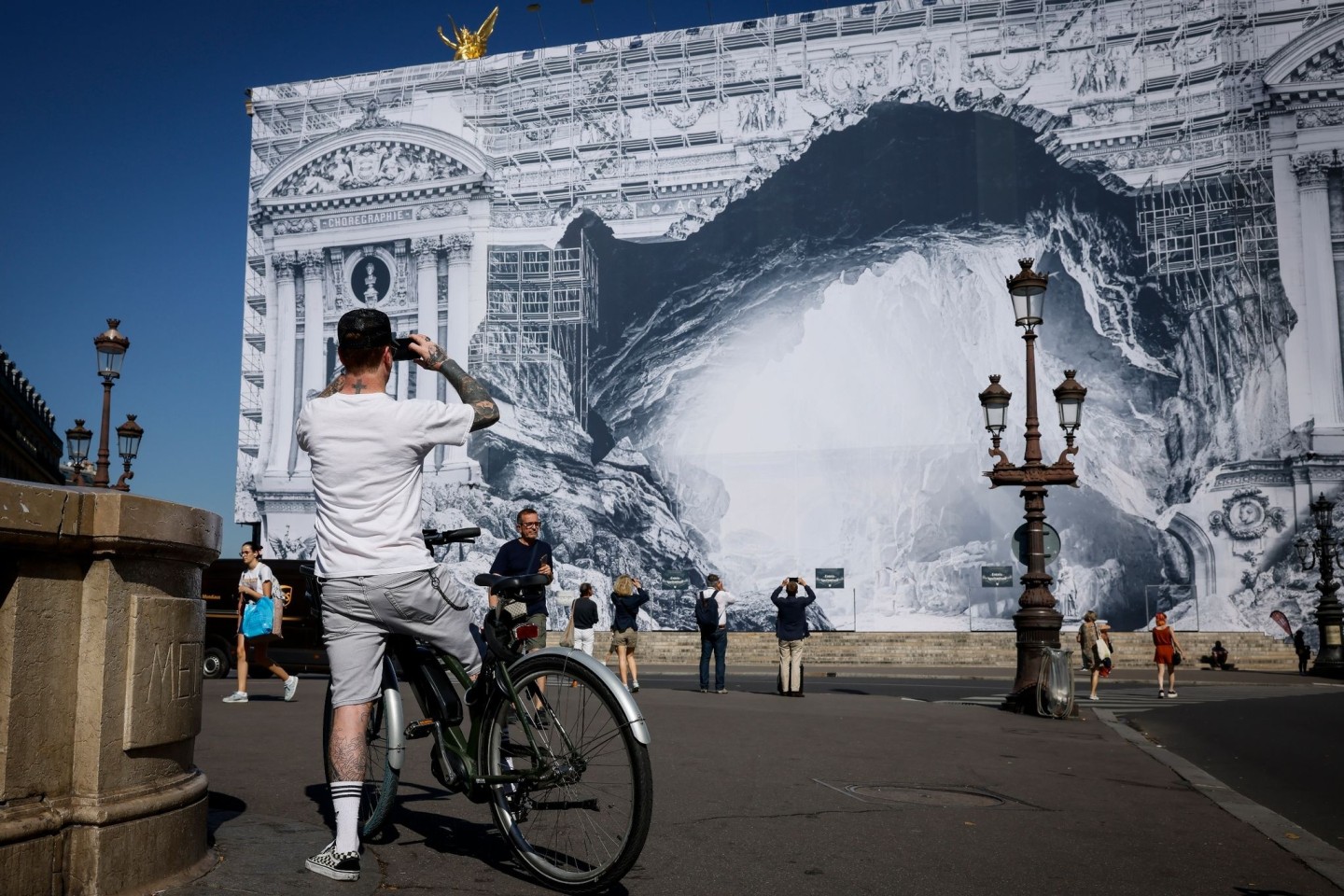 Ein Fahrradfahrer ist vor der verzierten Opera Garnier in Paris unterwegs.