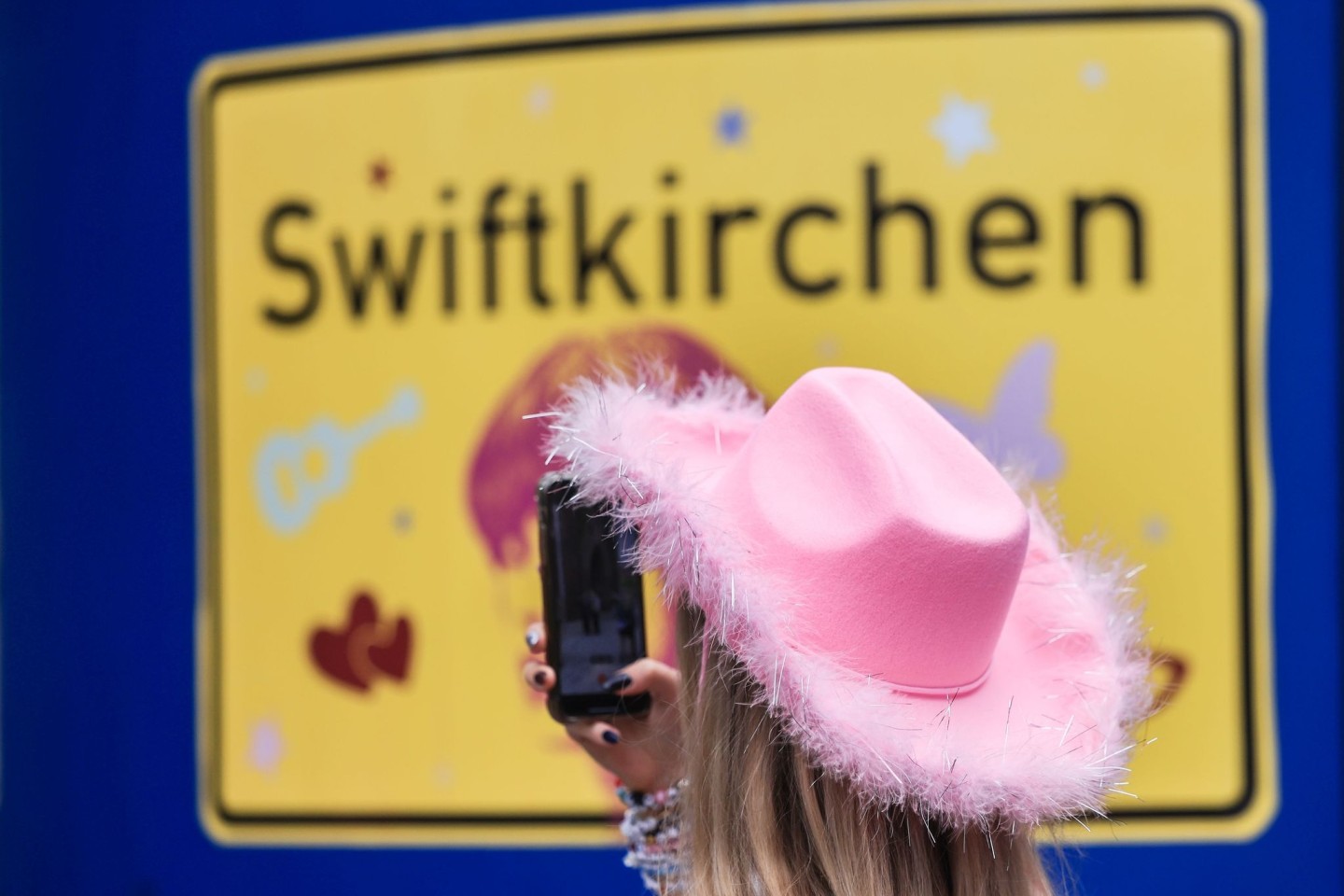 Ein Fan fotografiert vor dem Konzert der Sängerin Taylor Swift in Gelsenkirchen ein «Swiftkirchen»-Schild. Während des Konzerts am Abend zog der Datenverbrauch in den Handynetzen in der ...