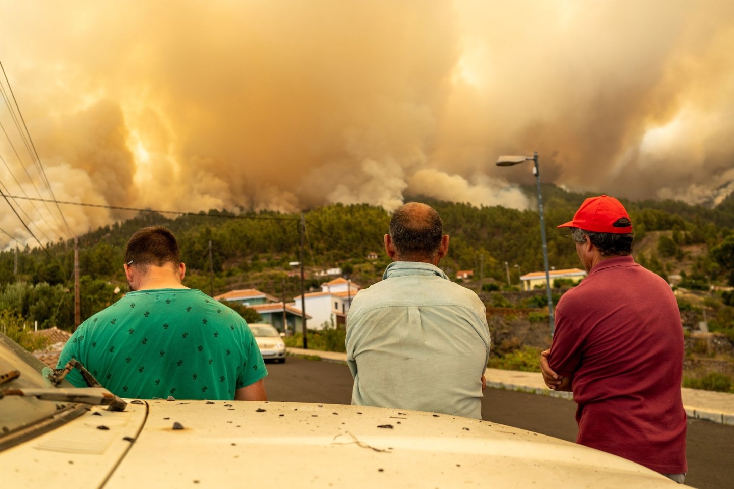 Drei Männer beobachten den Waldbrand auf der Kanareninsel.